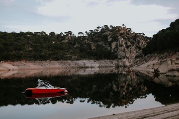  photograph of a swamp with a boat in red that is reflected as the rest of the landscape in the water