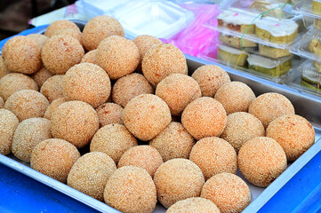 Closeup of Golden Fried Sesame Balls (Thai dessert) placed on a silver metal tray for street food at Thailand. Healthy food concept, selective soft focus.
