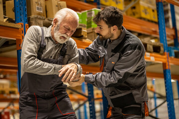 Warehouse situation, young worker comes to help senior worker, he got injured when carring heavy boxes