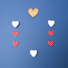Hearts in various sizes and colors forming a frame shape with copy space on a blue background. Minimal Love scene.