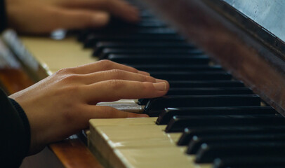 Two hands on the piano keys. A child plays the piano. The musician plays the piano. Close to the musician's hands