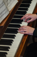 Two hands on the piano keys. A child plays the piano. The musician plays the piano. Close to the musician's hands