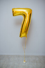 golden number 7 foil balloon on black background