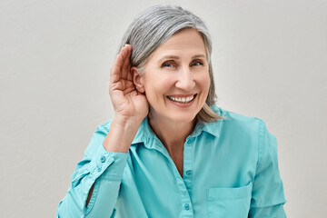 Mature woman listening sound with hand near ear for hearing check-up. Hearing test concept - obrazy, fototapety, plakaty