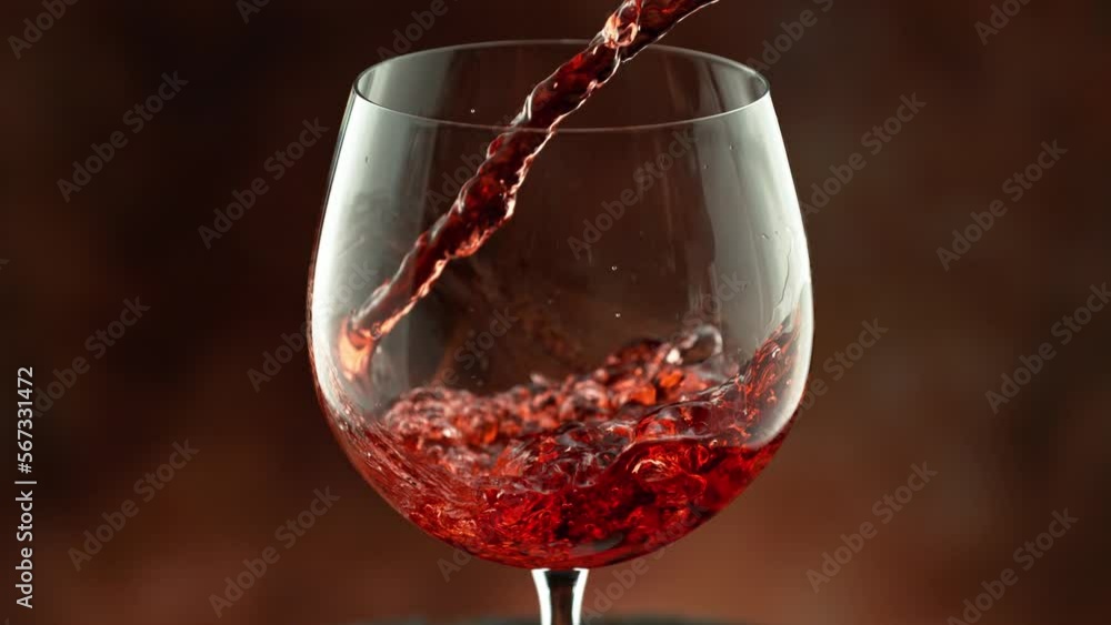 Wall mural super slow motion of pouring red wine into glass with speed motion. filmed on high speed cinema came