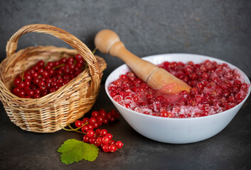 a basket of fresh red currants along with grated currants with sugar stand on a dark table