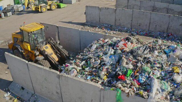 Skid steer loader operating on collecting and treatment disposal on the waste transfer station, high angle drone view.