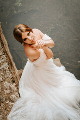 Fototapeta na wymiar Dreamy portraits of beautiful bride on stone riverbank