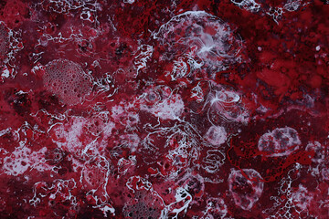 Spilled red and white paint on liquid thinner to form an abstract pattern.