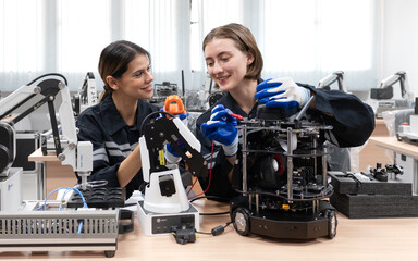 Computer science development engineer working on robotic arm connection and control at electronic futuristic technology center. Modern women training in industry 4.0 automated engineering workshop