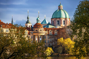 Fototapeta na wymiar Church of St. Francis of Assisi with green cupola, yellow autumn tree, Prague.