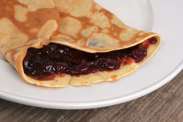 Crêpe roulée avec de la confiture dans une assiette en gros plan