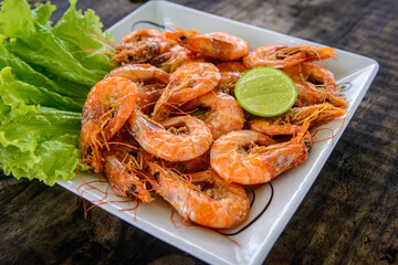 Shrimp sauteed with garlic and oil in white dish on wooden table. Brazilian food widely consumed on the coast.