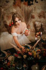 Beautiful bride by wedding table, richly decorated in rustic style