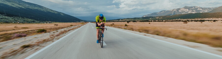Full length portrait of an active triathlete in sportswear and with a protective helmet riding a...