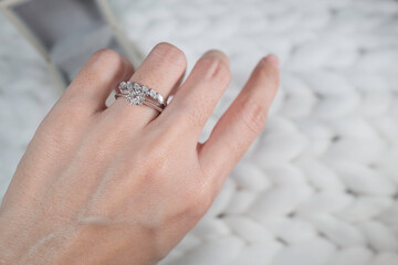 Close up of diamond ring on woman’s finger. Love, valentine, relationship and wedding concept....
