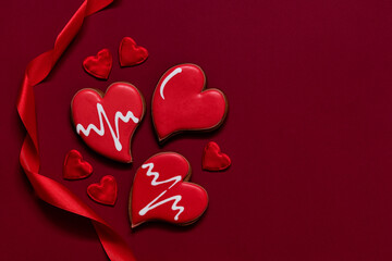 Red heart shaped cookies and red satin ribbon on a burgundy background for Valentine's day. Love...