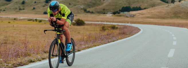 Full length portrait of an active triathlete in sportswear and with a protective helmet riding a...