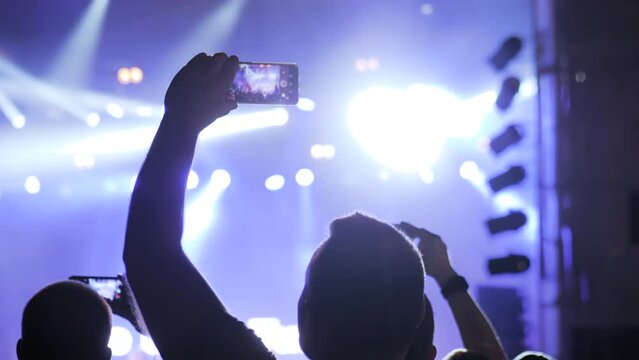 Man Hands Silhouette Taking Photo Or Recording Video Of Live Music Concert With Smartphone In Front Of Stage Of Nightclub - Close Up, Lens Flares. Photography, Entertainment, Technology Concept