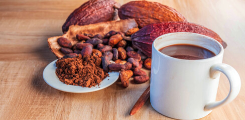 Hot cocoa cup with cocoa powder and cocoa beans on wooden background