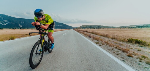 Obraz premium Full length portrait of an active triathlete in sportswear and with a protective helmet riding a bicycle. Selective focus 