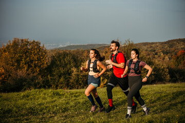 A diverse group of young people exercises outdoors, preparing for a mountain trail. They are wearing sports clothing and a trail running vest