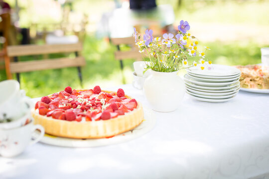 Familiennachmittag im Grünen mit  weißem Tischtuch , einem Blumensträußchen, Kaffee und Erdbeeertorte.