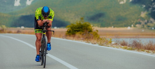 Full length portrait of an active triathlete in sportswear and with a protective helmet riding a...