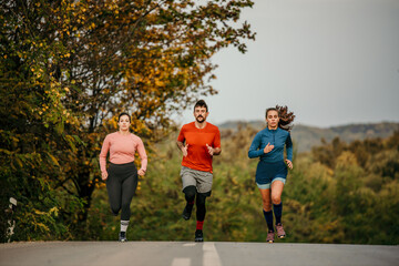 Fitness sports people running lifestyle concept. Group of dedicated young people jogging together outdoors