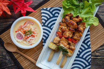 Yakitori and Chawan Mushi - Japanese chicken skewer and steamed egg flat lay on wood table at top view