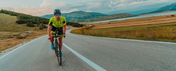 Full length portrait of an active triathlete in sportswear and with a protective helmet riding a...