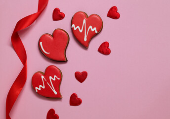 Valentine's Day composition with red heart shaped gingerbread and red satin ribbon on a pink...