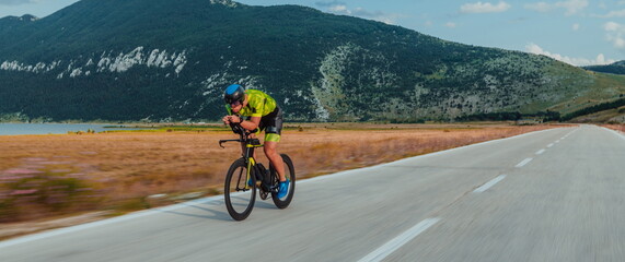 Full length portrait of an active triathlete in sportswear and with a protective helmet riding a...