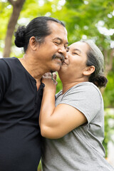 Happy smiling old senior couple staying together, old aged wife kissing her life partner husband