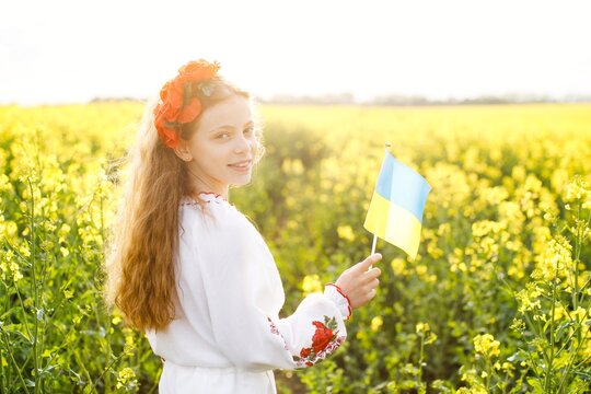 Pray for Ukraine. Child with Ukrainian flag in rapeseed field. Little girl holding national flag in her hand. Happy kid celebrating Independence Day.
