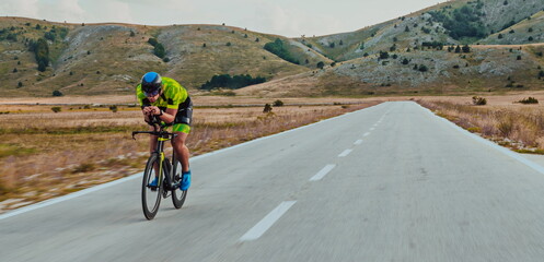 Full length portrait of an active triathlete in sportswear and with a protective helmet riding a bicycle. Selective focus 