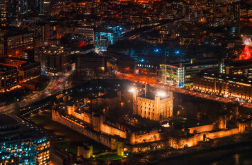 Fototapeta na wymiar Aerial view of illuminated London tower, orange yellow street lights starting glowing to streets