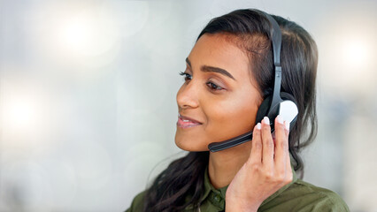 Happy female customer service agent smiling while working in a call centre and talking to a client...