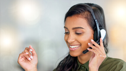 Happy female customer service agent smiling while working in a call centre and talking to a client...