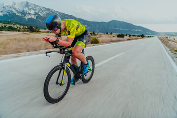 Full length portrait of an active triathlete in sportswear and with a protective helmet riding a bicycle. Selective focus 