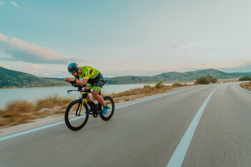 Full length portrait of an active triathlete in sportswear and with a protective helmet riding a...