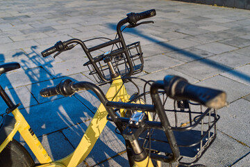 Yellow electrical bicycles with baskets in the parking lot