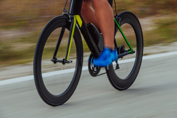Close up photo of an active triathlete in sportswear and with a protective helmet riding a bicycle....