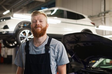 Portrait of a successful car mechanic in a clean uniform against the background of modern service station equipment