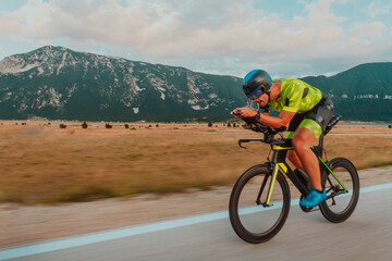 Full length portrait of an active triathlete in sportswear and with a protective helmet riding a...