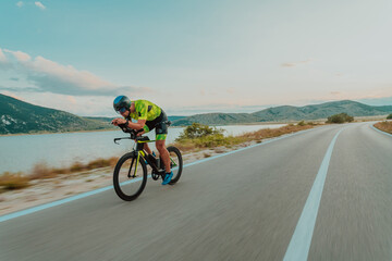 Full length portrait of an active triathlete in sportswear and with a protective helmet riding a...