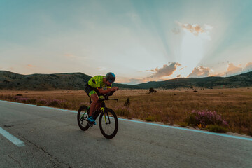 Full length portrait of an active triathlete in sportswear and with a protective helmet riding a...