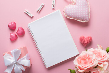 An open notebook with a gift and sweets on a light pink background. Valentine's day.