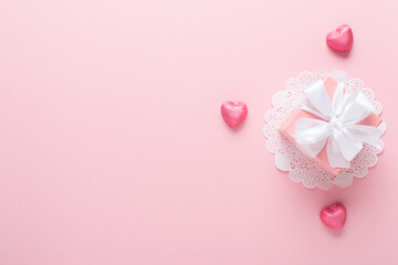 A mock-up of a Valentine's Day banner with a gift box, heart-shaped candies on a pink background.