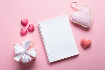 An open notebook with a gift and sweets on a light pink background. Valentine's day.